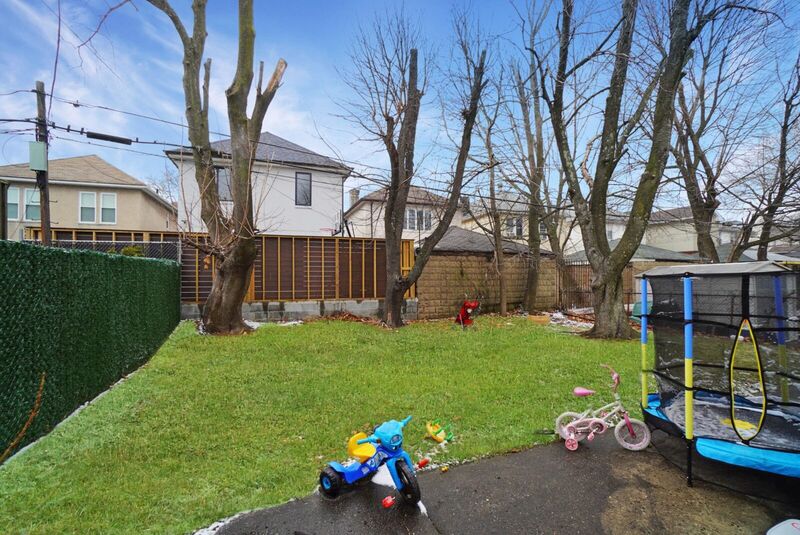 Backyard with grass, a trampoline and children's bikes